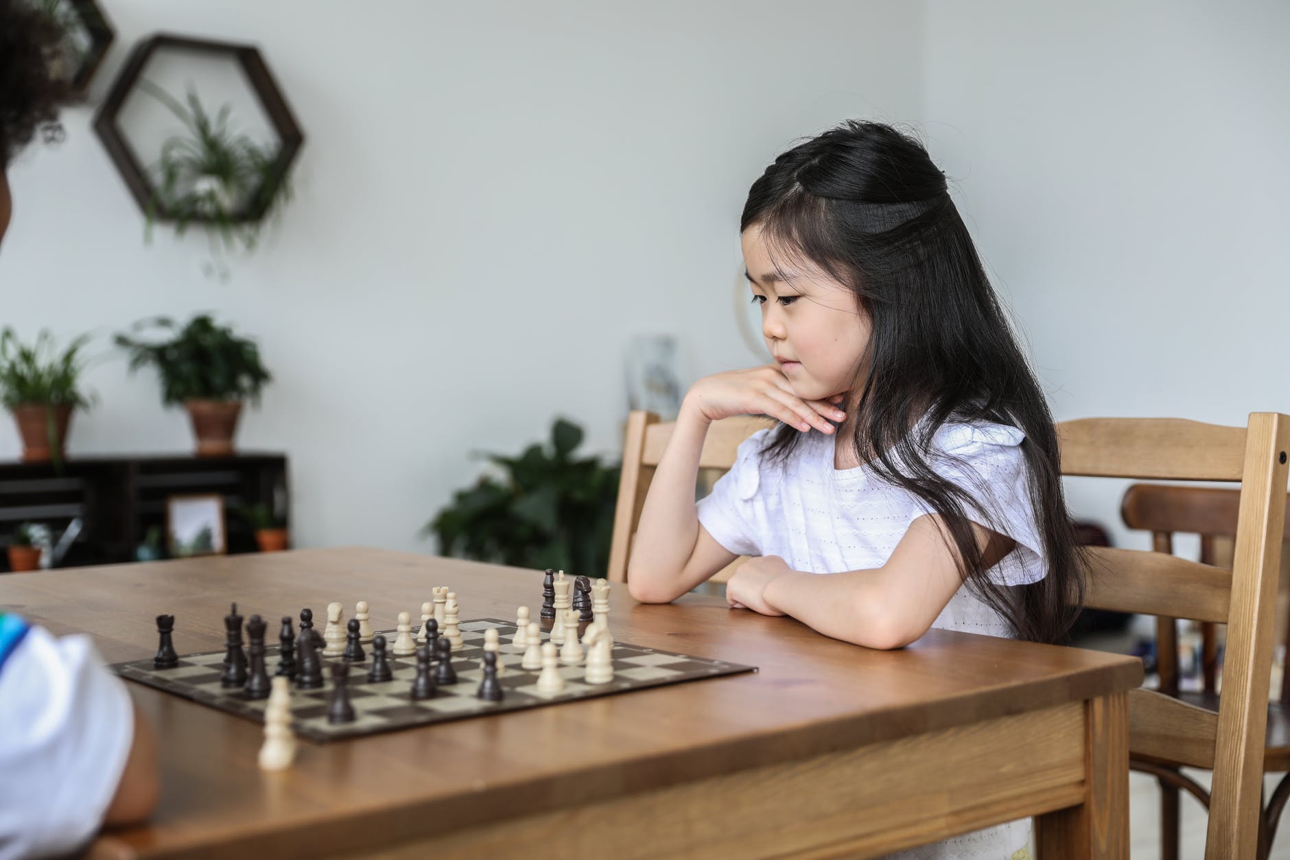 asian girl playing chess with hand at chin
