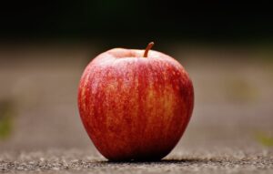 shallow focus photography of red apple on gray pavement